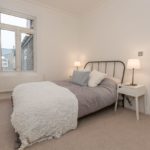 Bright cream second bedroom with window, throw and side table with side lamps