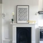 Fireplace in white living area with photo and flowers on mantelpiece